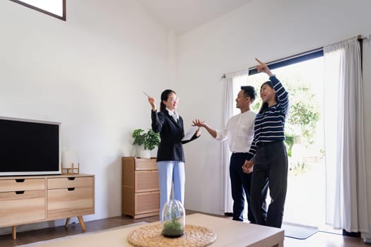 Young couple follow a real estate agent who is giving them a tour around a home, showing all the room and telling about all the advantage of living. Buying house or apartment concept.