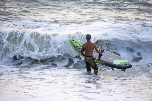 athletic wiry surfer guy swims with a paddle on a sup board in the sea Stand up paddleboarding