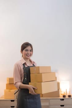 Asian woman entrepreneur prepare parcel box and check online order on laptop computer for commercial checking delivery. online marketing, packing box, SME seller. startup business concept.