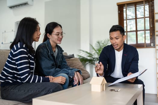 young lesbian married couple discussing agreement with skilled real estate agent or broker. Professional financial advisor or saleswoman explaining contract detail.