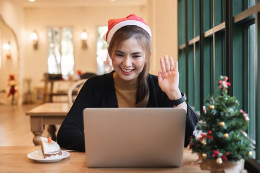A businesswoman sits and work using a laptop in an office decorated with a Christmas tree and colorful lights during the holiday season. Spend Christmas at work.