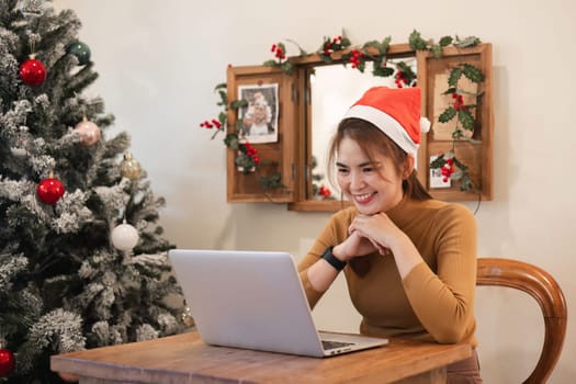 A startup employee writes a report on a laptop on Christmas Eve. In an office decorated with colorful bulbs and lights during the Christmas holidays.