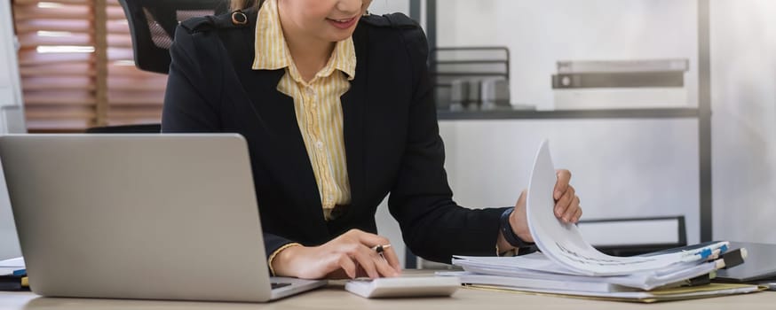 Close up, Businesswoman uses calculator to calculate finances, mathematics on table in office and business charts, tax, accounting, statistics and analytical research concept..