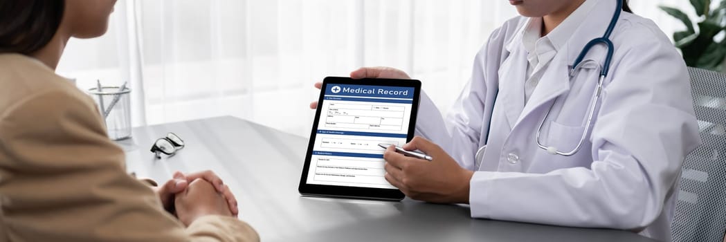 Doctor show medical diagnosis report on tablet and providing compassionate healthcare consultation while being supportive and holding young patient hand in doctor clinic office. Neoteric