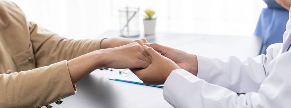 Doctor show medical diagnosis report and providing compassionate healthcare consultation while holding young patient hand for being supportive and professional in doctor clinic office. Neoteric