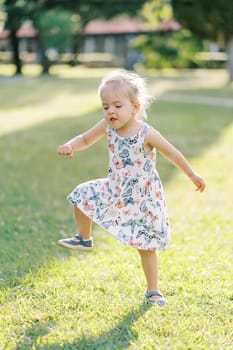 Little girl funny stamping her feet in a sunny meadow and waving her arms. High quality photo