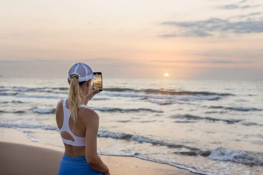 girl runner runs along the beach in sportswear. the girl takes a photo of the sunrise at sea before jogging, there is a place for an inscription. High quality photo