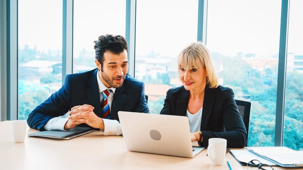 Two business people talk project strategy at office meeting room. Businessman discuss project planning with colleague at modern workplace while having conversation and advice on financial report. Jivy