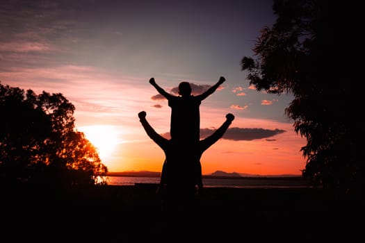 Father and son walking on the field at the sunset time. Concept of friendly family. High quality photo