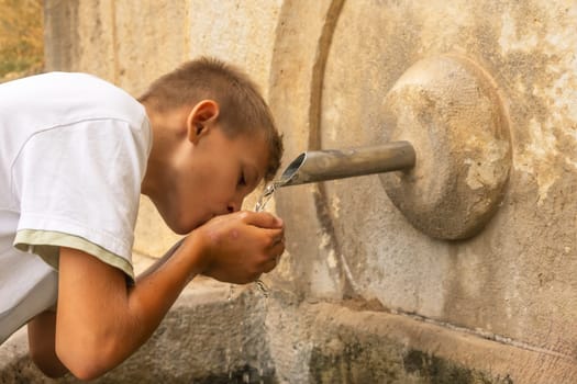 teenage boy drinks water from a spring.there is a place for an inscription High quality photo