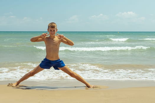 A happy boy of European appearance is walking on the beach. Summer holiday concept. High quality photo