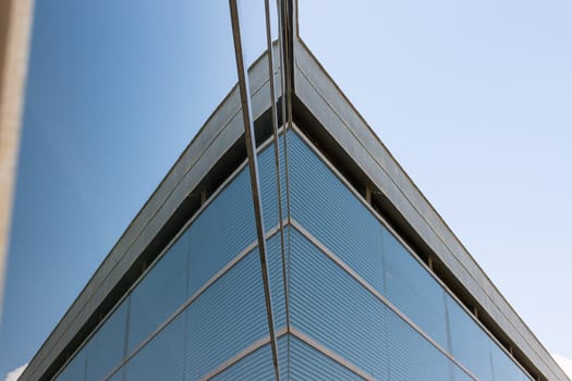 Low angle view of the glass facade of a tall office building against a clear blue sky, there is space for an inscription. High quality photo