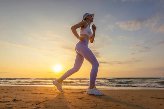 silhouette of a sports girl against the background of the sea at dawn, the girl stands in leggings and a top, in a cap against the background of the sea. High quality photo