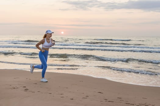 silhouette of a sports girl against the background of the sea at dawn, the girl stands in leggings and a top, in a cap against the background of the sea. High quality photo