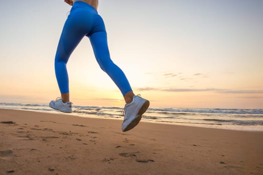 legs of a girl in leggings and sneakers running along the beach at dawn with space for inscription. High quality photo