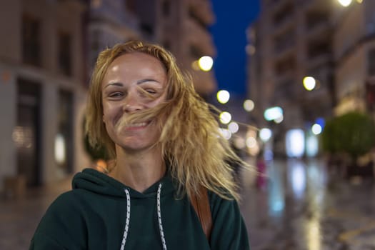 Beautiful girl smiles in the evening, the girl has blond hair, the girl shakes her head, selective focus. High quality photo