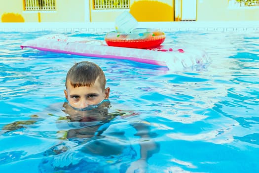 Happy boy swims and dives underwater. Active healthy lifestyle, water sports and activities with parents on summer family vacation with child. High quality photo