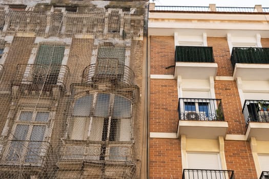 An old house is being restored, the whole house will be covered with netting so that nothing falls on people during the restoration. High quality photo