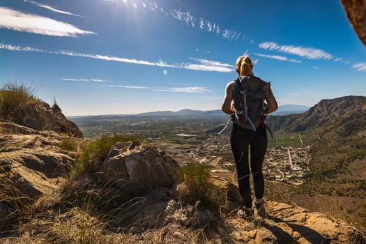 Hiker with backpack standing on top of the mountain and enjoying valley view at sunrise. High quality photo