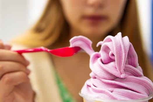 teenage girl eats purple ice cream, the focus on the ice cream background is blurred, there is a place for the inscription. High quality photo