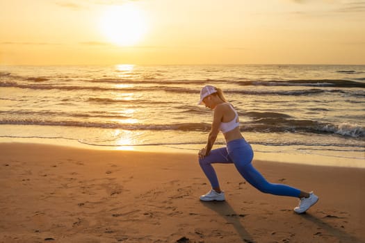 a girl of European appearance in sportswear does a warm-up at dawn on the sea, there is a place for an inscription. High quality photo