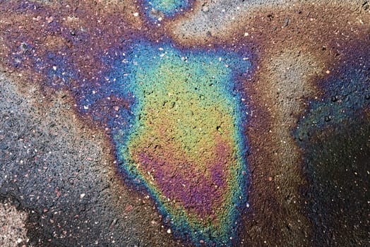 Textured stain of fuel or oil on wet asphalt on a rainy day