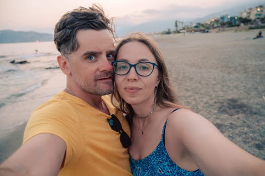 Happy couple taking a photo on a beach at the sea in Alanya city, Turkey. Travelling or vacation concept