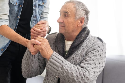 Grown up son asking for apologizes to offended stressed elderly senior daddy, sitting together on couch. Compassionate young man supporting, giving psychological help to frustrated middle aged father. High quality photo