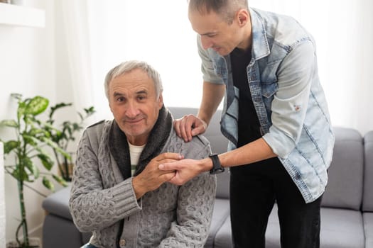 Grown up son asking for apologizes to offended stressed elderly senior daddy, sitting together on couch. Compassionate young man supporting, giving psychological help to frustrated middle aged father. High quality photo