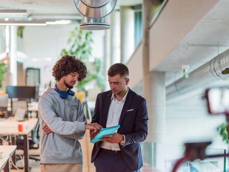 In a modern office setting, an African American businessman engages in a discussion with his director, using a tablet to address business challenges, symbolizing collaboration and technology integration in corporate decision-making.