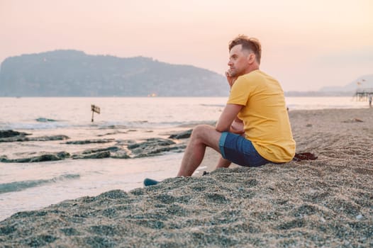 Man sits on the beach and looks at the sea in Alanya city, Turkey. Travelling or vacation concept