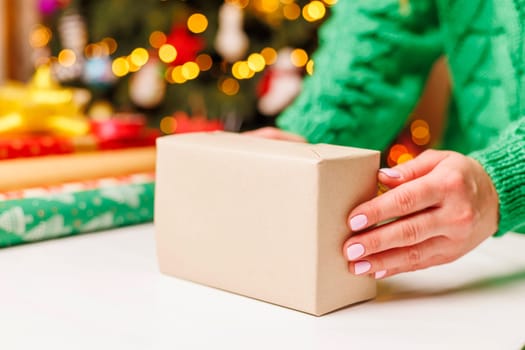 Young woman wrapping gifts at table in living room.