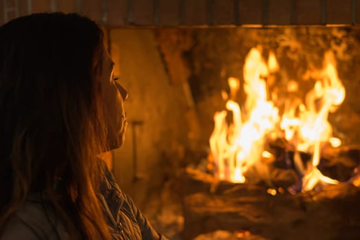 latin woman in front of the fireplace, in a moment of relaxation and peace during the harsh winter days in europe.