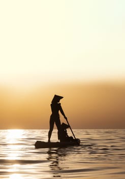 woman with a child on a sup board in the sea swim against the background of a beautiful sunset, Standup paddleboarding