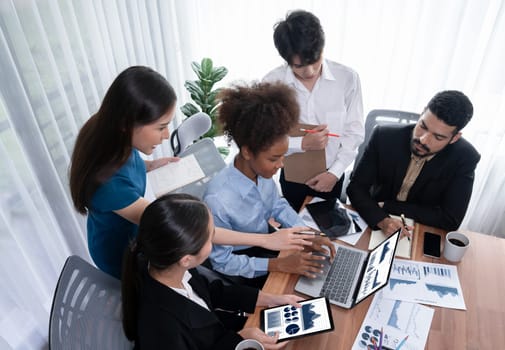 Multiracial analyst team use BI Fintech software to analyze financial data on meeting table. Financial dashboard data display on laptop screen with analyzed chart for marketing indication. Concord