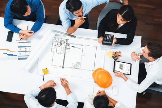 Top view banner of diverse group of civil engineer and client working together on architectural project, reviewing construction plan and building blueprint at meeting table. Prudent