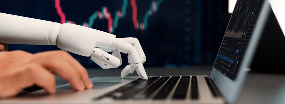 Automated stock trading concept. Robotic and human hand analyzing financial data on stock exchange, artificial intelligence utilization to predict precise price change in stock market. Trailblazing