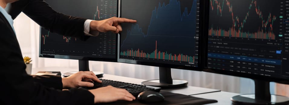 Group of traders discussing on office desk, monitoring stock market on monitor at office workplace. Businessman and broker analyzing stock graph together at stock trading company. Trailblazing