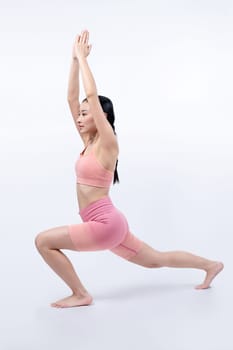 Asian woman in sportswear doing yoga exercise in standing pose on fitness as her workout training routine. Healthy body care and meditation yoga lifestyle in full shot on isolated background. Vigorous