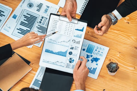 Top view diverse group of business analyst team analyzing financial data report paper on meeting table. Chart and graph dashboard by business intelligence analysis. Meticulous