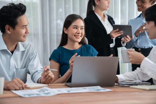 Multiracial analyst team use BI dashboard data to analyze financial report on meeting table. Group of diverse business people utilize data analysis by FIntech for success business marketing. Concord