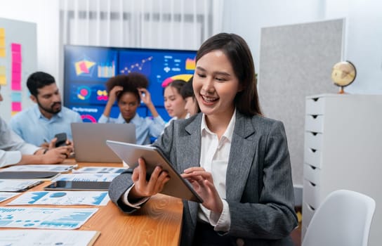 Portrait of happy young asian businesswoman with group of office worker on meeting with screen display business dashboard in background. Confident office lady at team meeting. Concord