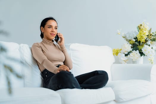 Relaxed young African American woman using crucial mobile phone on sofa couch in living room at home