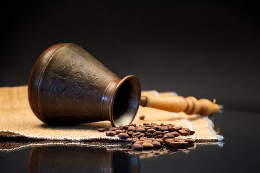 natural coffee beans, Turkish coffee pot on burlap, isolated on a black background