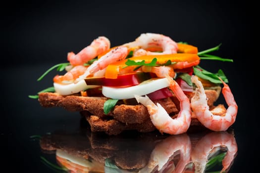 cooked sandwich with shrimp, eggs, pepper and greens, isolated on black background
