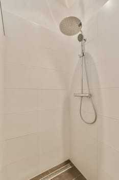 a shower with white tiles on the wall and brown tile flooring in a modern style bathroom at an apartment