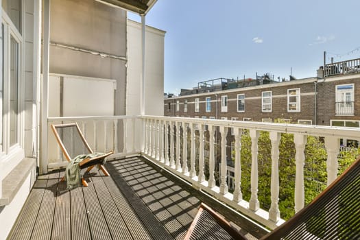 a balcony with a chair on the left and an open door to the back yard in the photo is clear blue sky