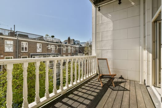 a balcony with white railings and green plants on the balknotn, london apartment block in the background