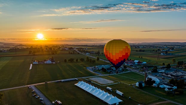 An Aerial View of a Multi-Colored Hot Air Balloon, Floating Over Pennsylvania Farmlands at Sunrise, on a Summer Day