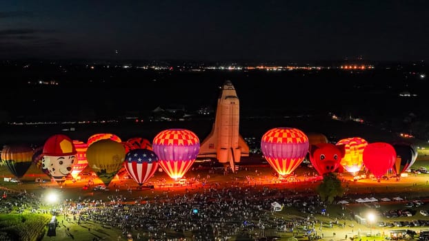 Bird in Hand, Pennsylvania, September 15, 2023 - An Aerial View of a Line of Performing Hot Air Balloons Glow on a Summer Evening